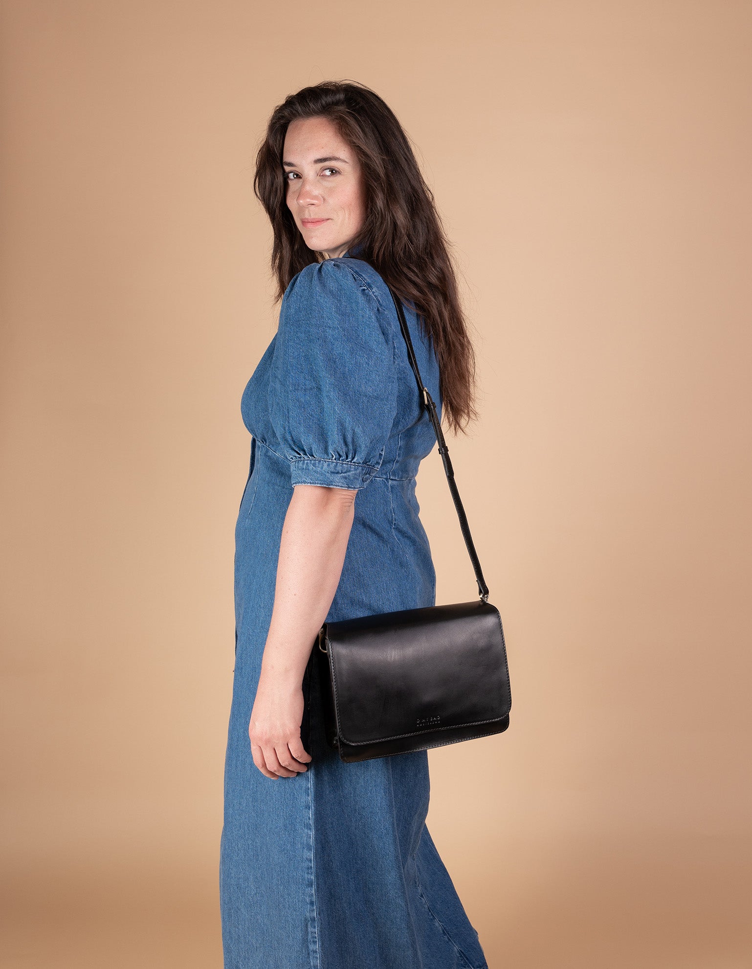 Black Leather womens handbag. Square shape with an adjustable strap. Model product image