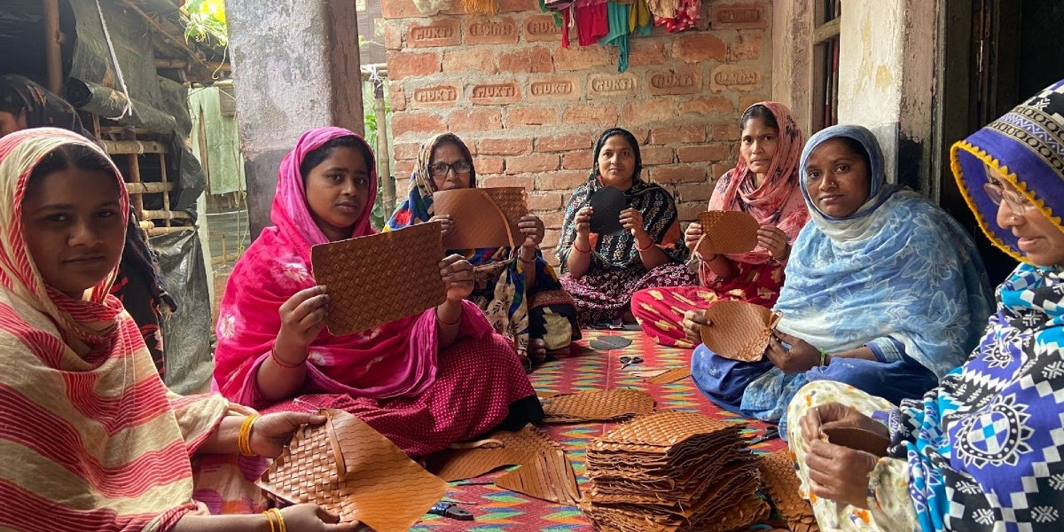 A group of women from Kolkata, India, sitting together on the floor showing how O My Bag's Woven Leather is made.