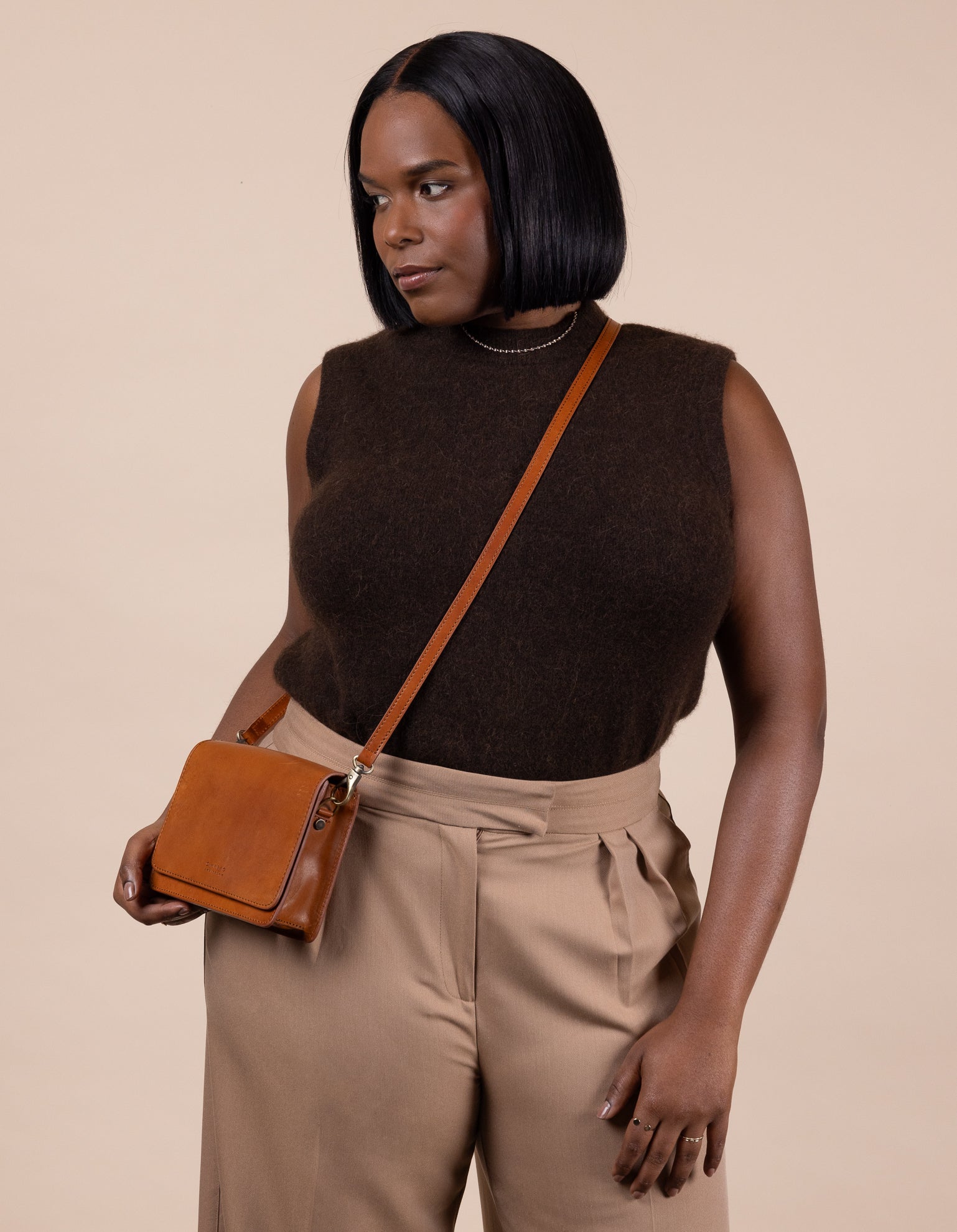 Audrey Mini Cognac leather bag. Square shape with an adjustable leather strap. Model image