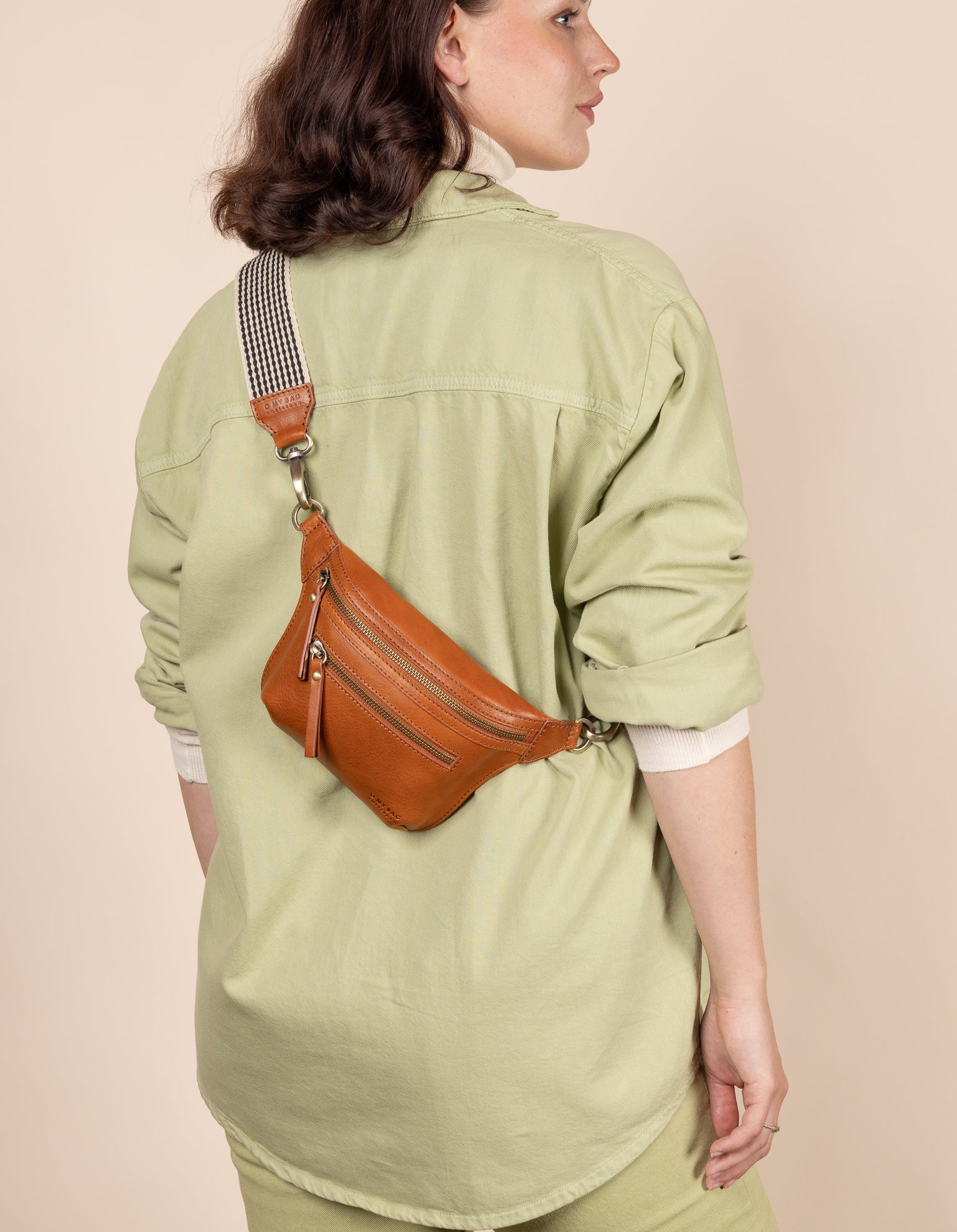 Cognac Leather womens fanny pack. Square shape with an adjustable strap. Model product image