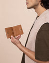 Alex fold over wallet in cognac apple leather - model holding it open