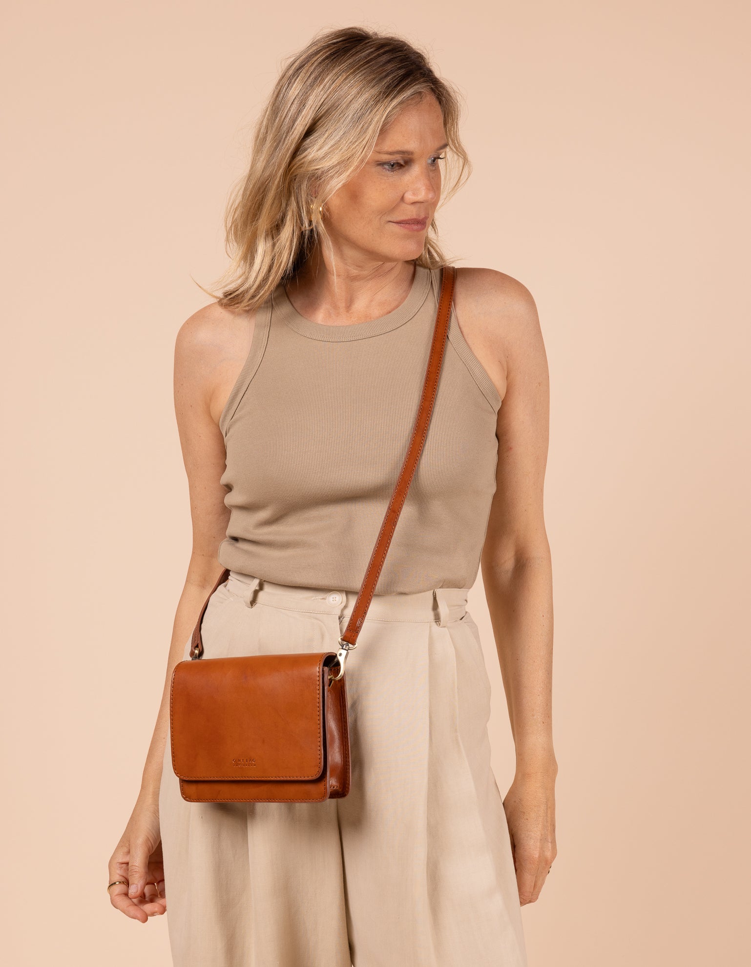 Model image of Audrey Mini cognac classic leather crossbody bag with adjustable leather strap