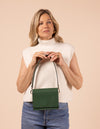 Model image showcasing Audrey Mini pine green classic leather crossbody bag with shoulder leather strap