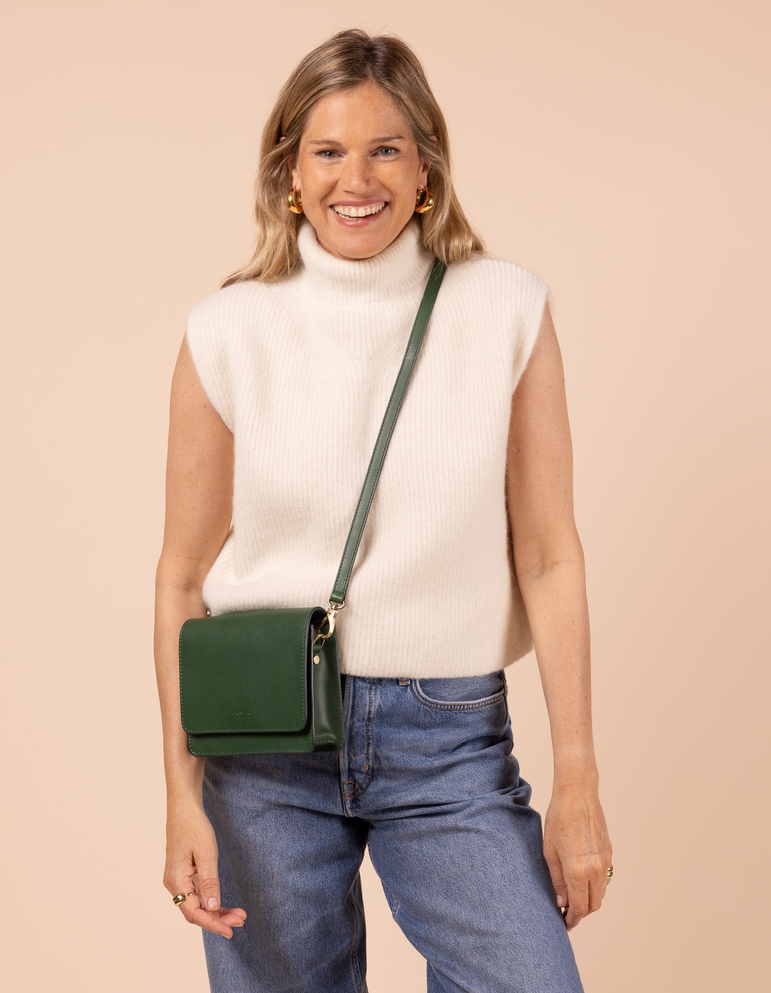 Model image showcasing Audrey Mini pine green classic leather crossbody bag with adjustable leather strap