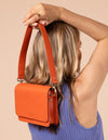 Model image showcasing Audrey Mini tangerine classic leather crossbody bag with shoulder leather strap