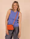 Model image showcasing Audrey Mini tangerine classic leather crossbody bag with adjustable leather strap