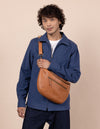Drew Maxi in wild oak leather ft. adjustable leather strap. Male model product image.