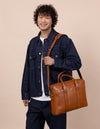 Harvey in cognac classic leather, male model product image with adjustable strap.