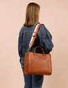 Model image with a brown leather bag and an orange and white cotton strap