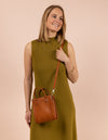 Small leather mini tote bag in brown with a thin cross-body strap, model image
