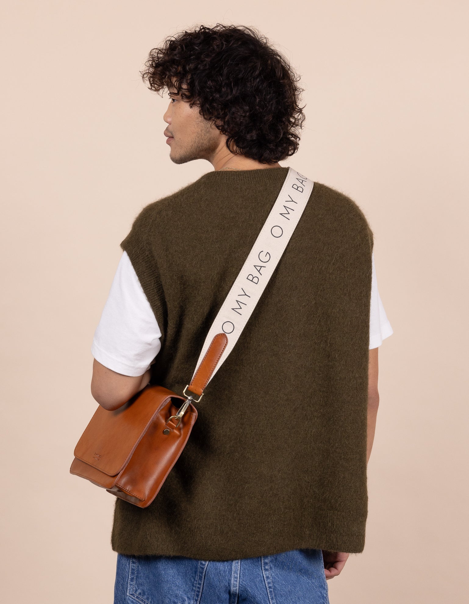 Model with Audrey bag in cognac classic leather and canvas logo strap in white canvas and cognac classic leather