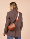 Model image showcasing Maya cognac classic leather crossbody bag with adjustable leather strap