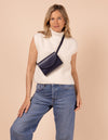 Ecom model image of blond woman model wearing a small navy belt bag across her chest