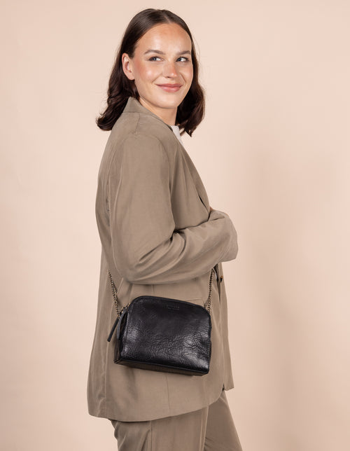 Black Leather womens handbag. Square shape with an adjustable leather & chain strap.Model image.