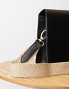 Organic cotton webbing strap in sand with black leather - Strap hooked on a bag placed on a table