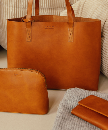 Two brown leather bags on a white couch