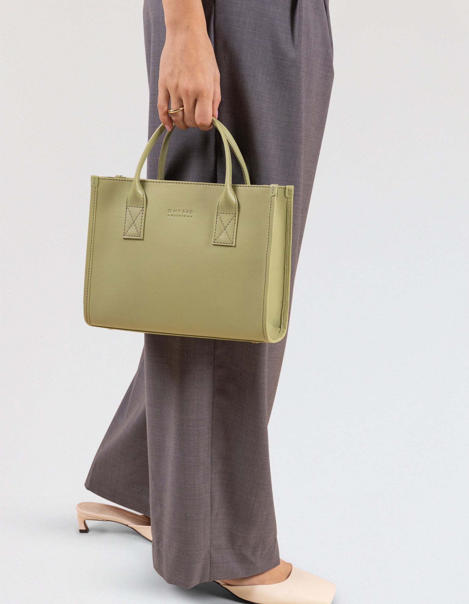 Model wearing the Jackie Midi bag in Tea Green-coloured leather
