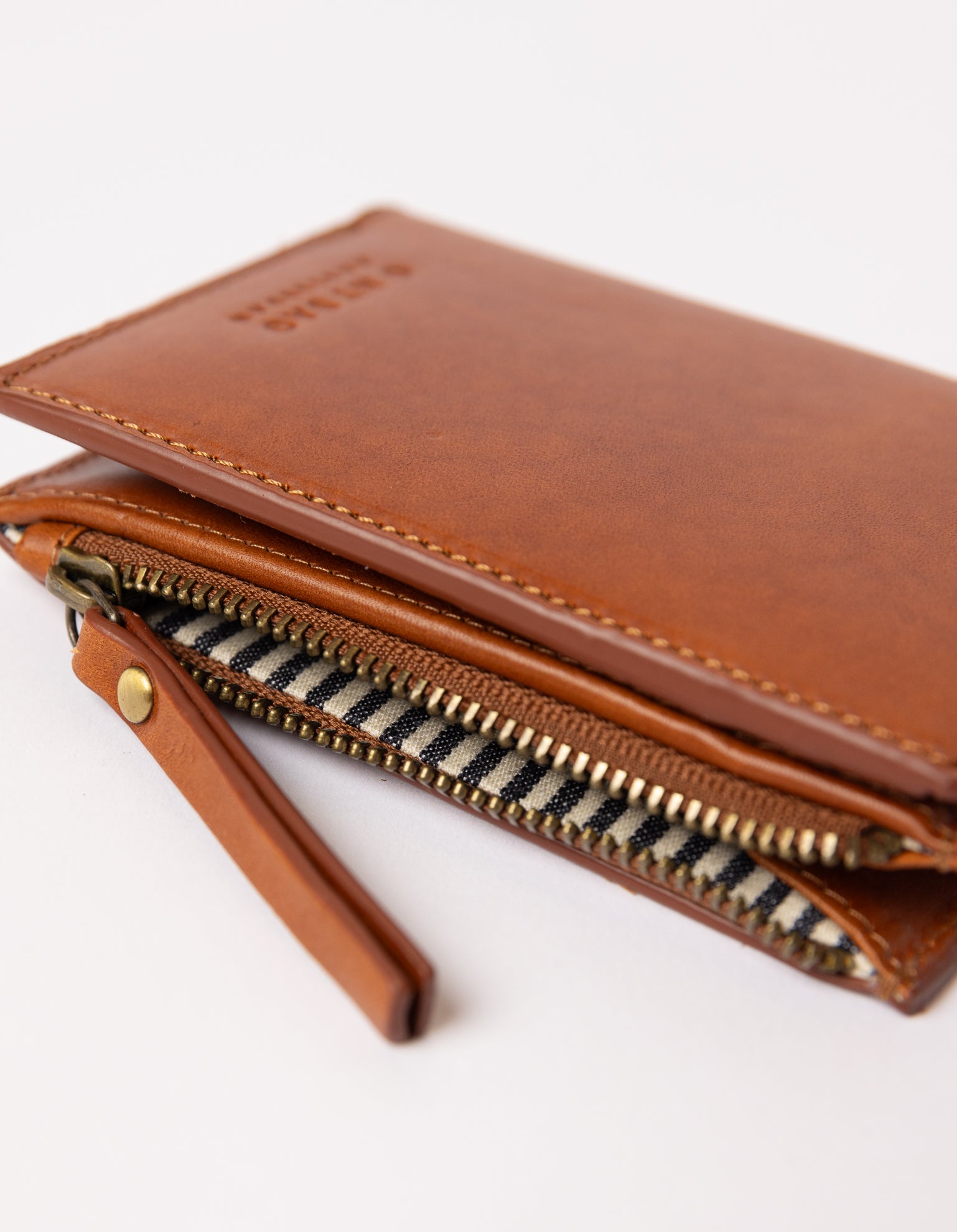 cognac wallet layed down on white background - close up of open zipper and zipper handle