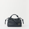 Blue leather handbag with knotted handle on a light gray background