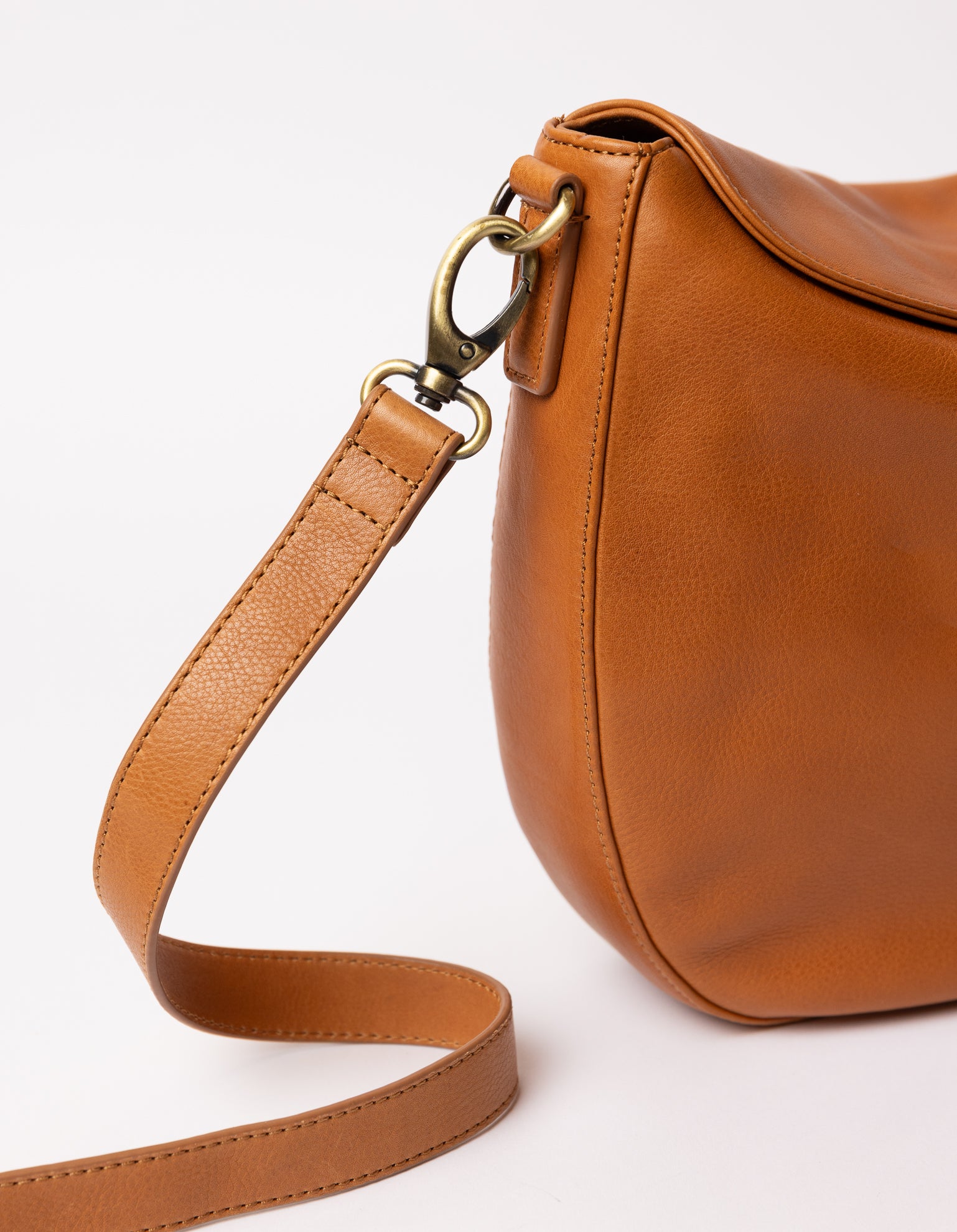 cognac bag on white background - close up of cognac classic leather strap hooked on the bag