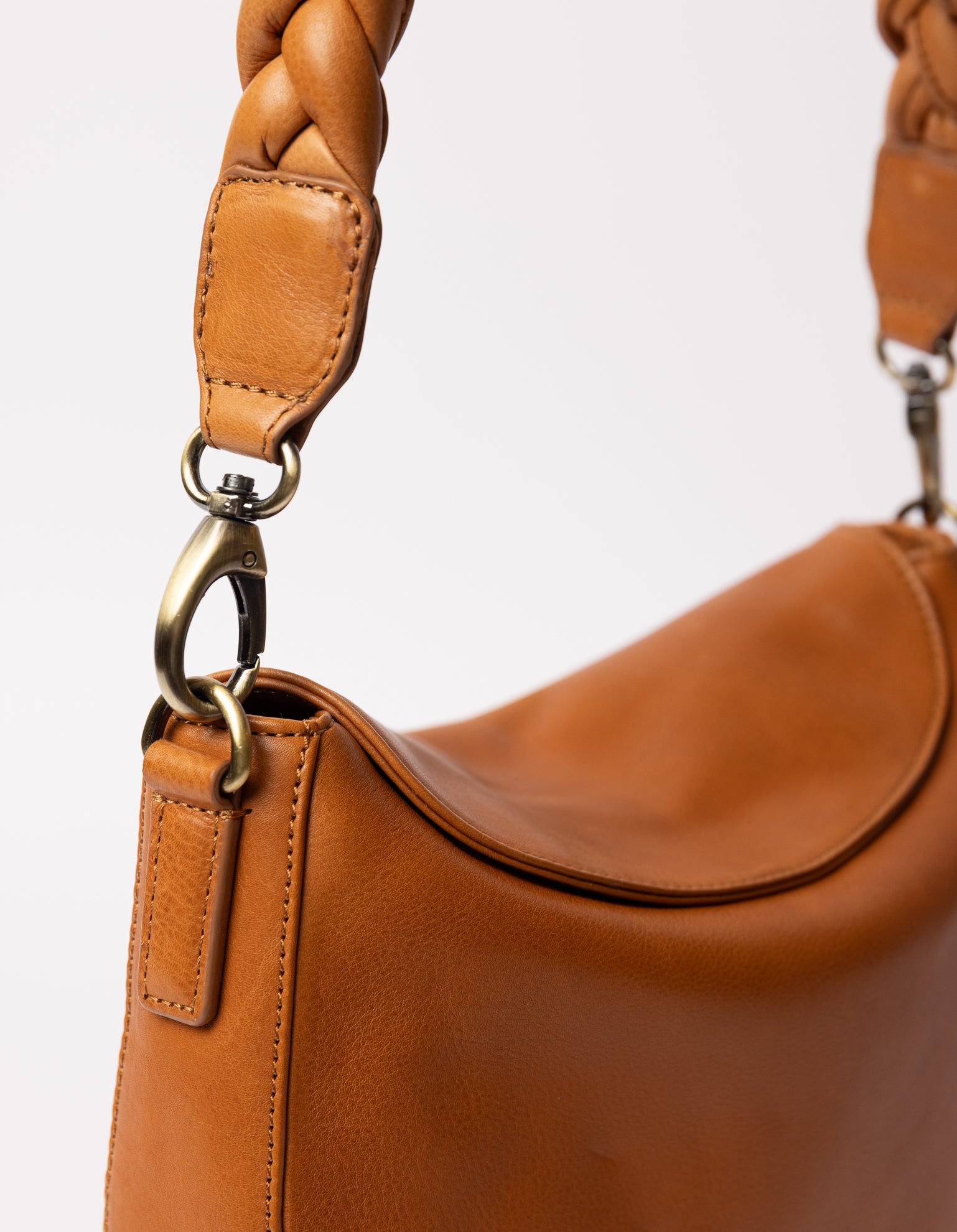 cognac bag on white background - close up of bag hanging on braided cognac strap