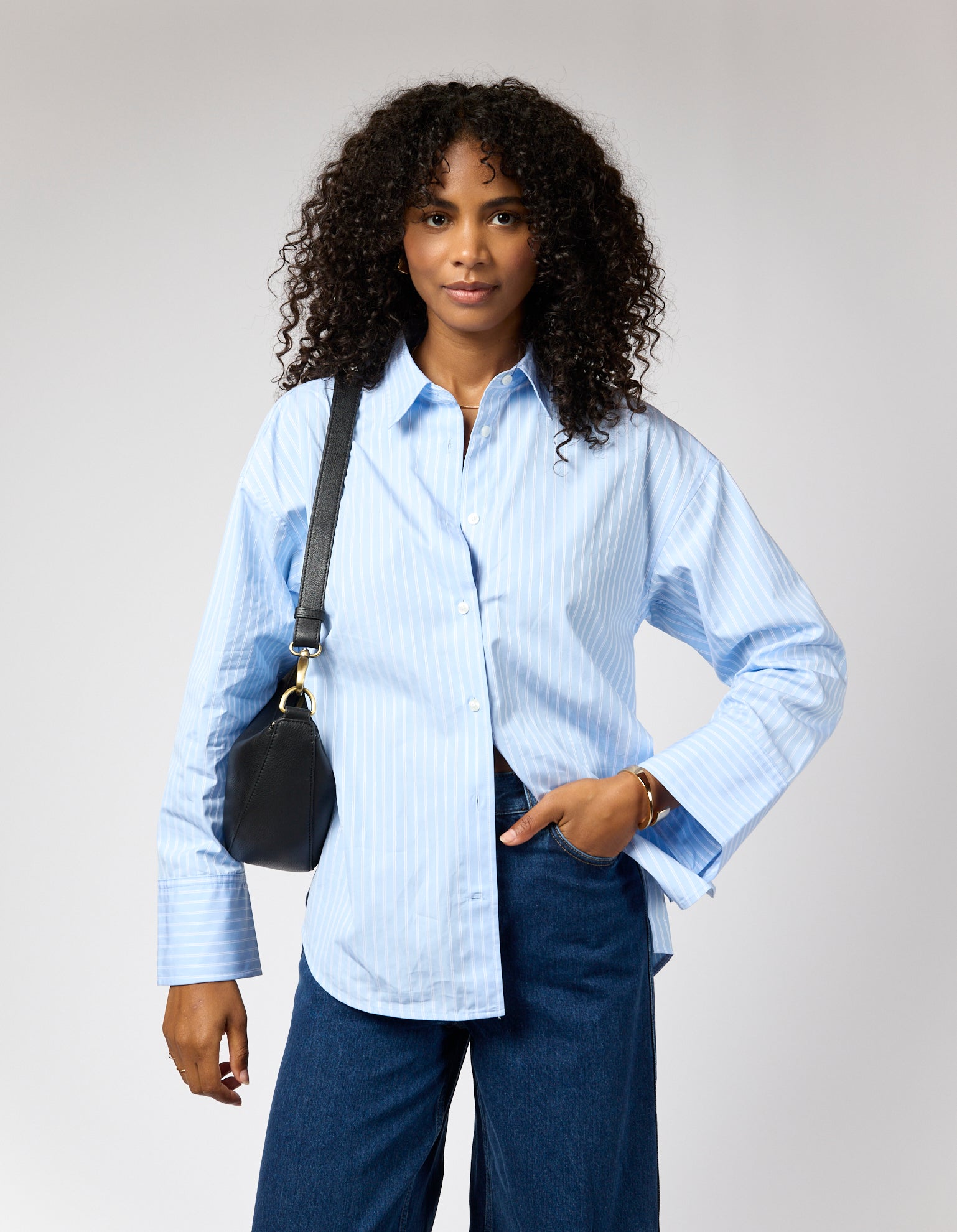 Female model with blue shirt and black leather bag on shoulder