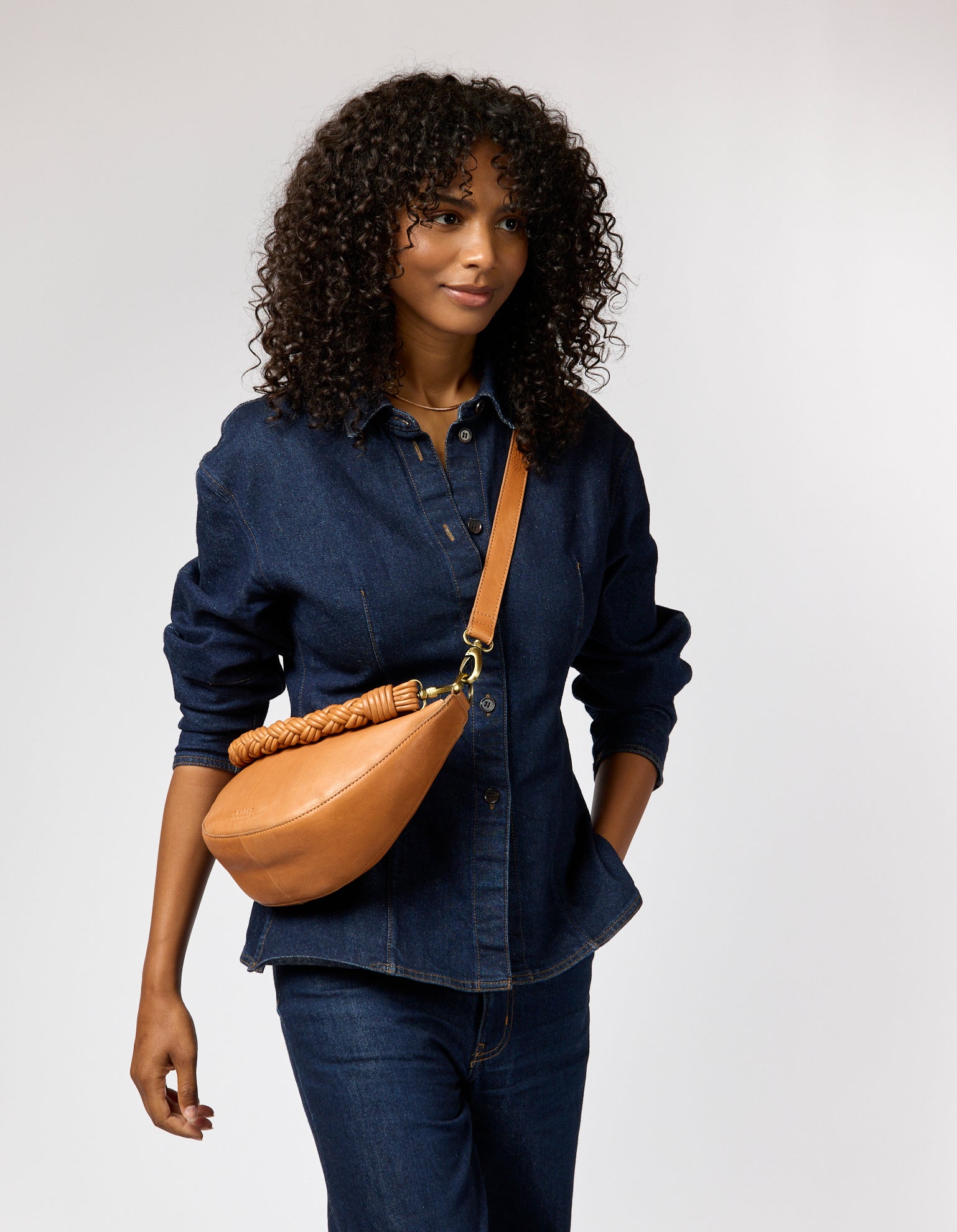 female model with denim outfit and brown leather bag with two straps
