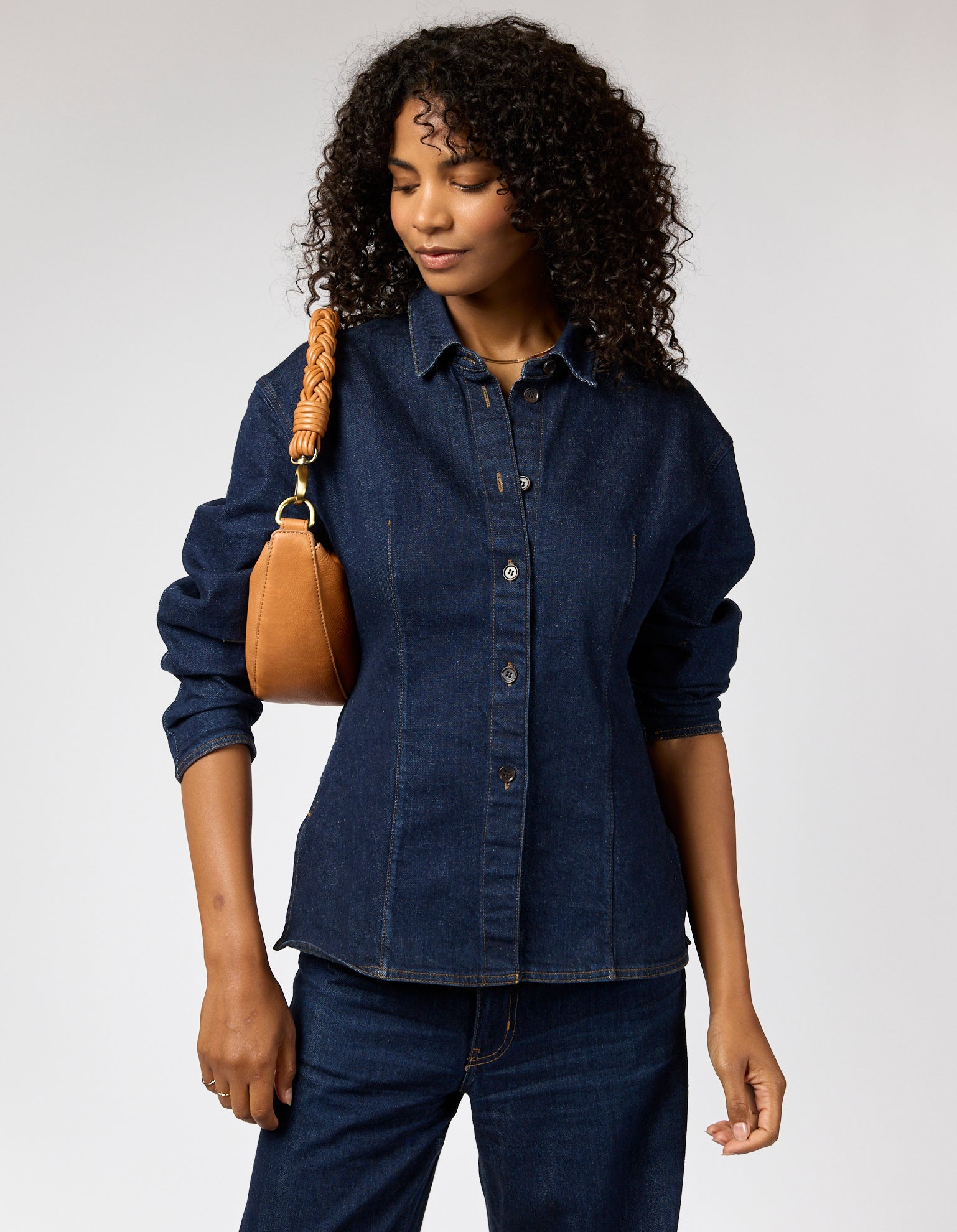 female model with denim outfit and brown leather bag with braided shoulder strap