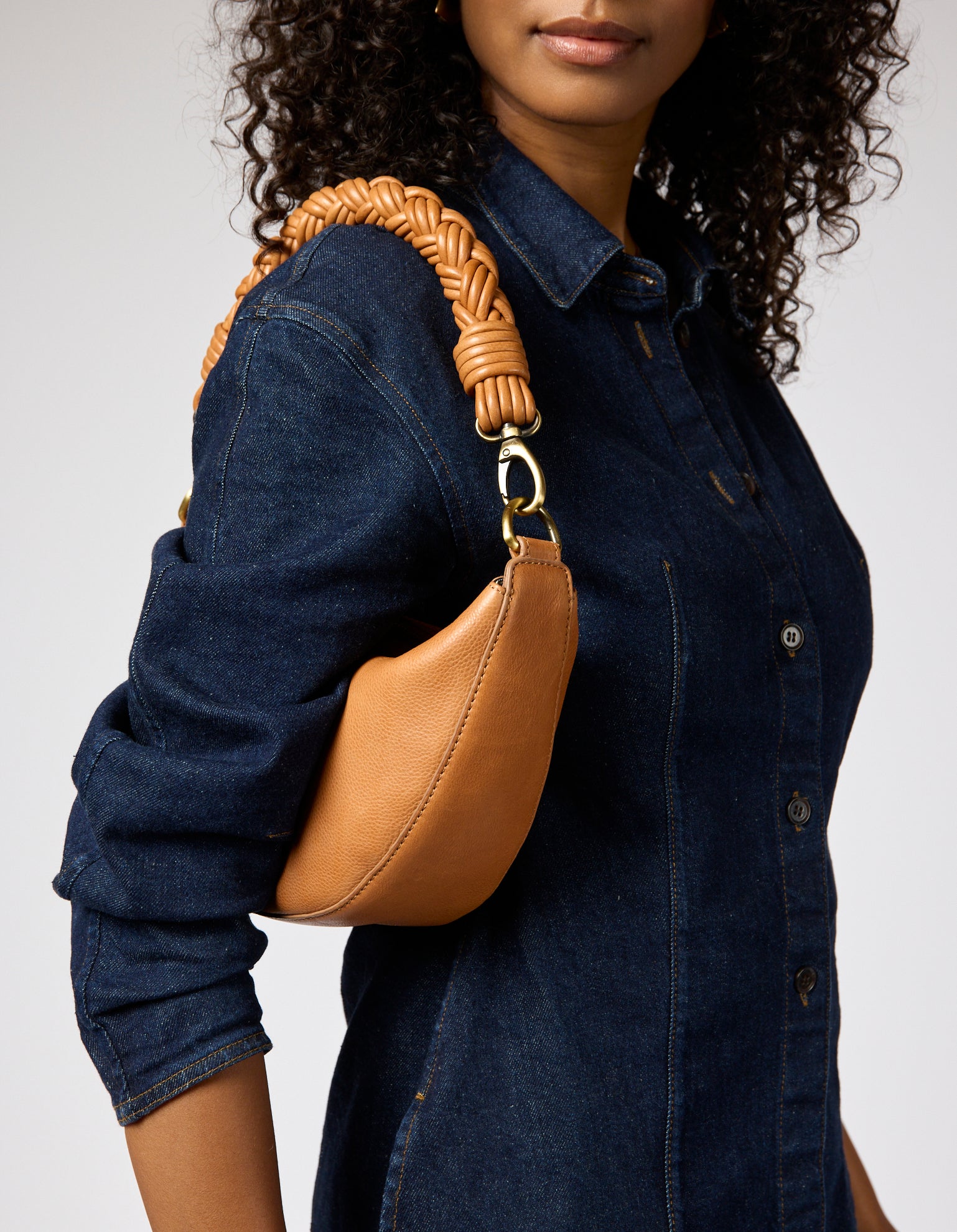 female model with denim outfit and brown leather bag with braided shoulder strap