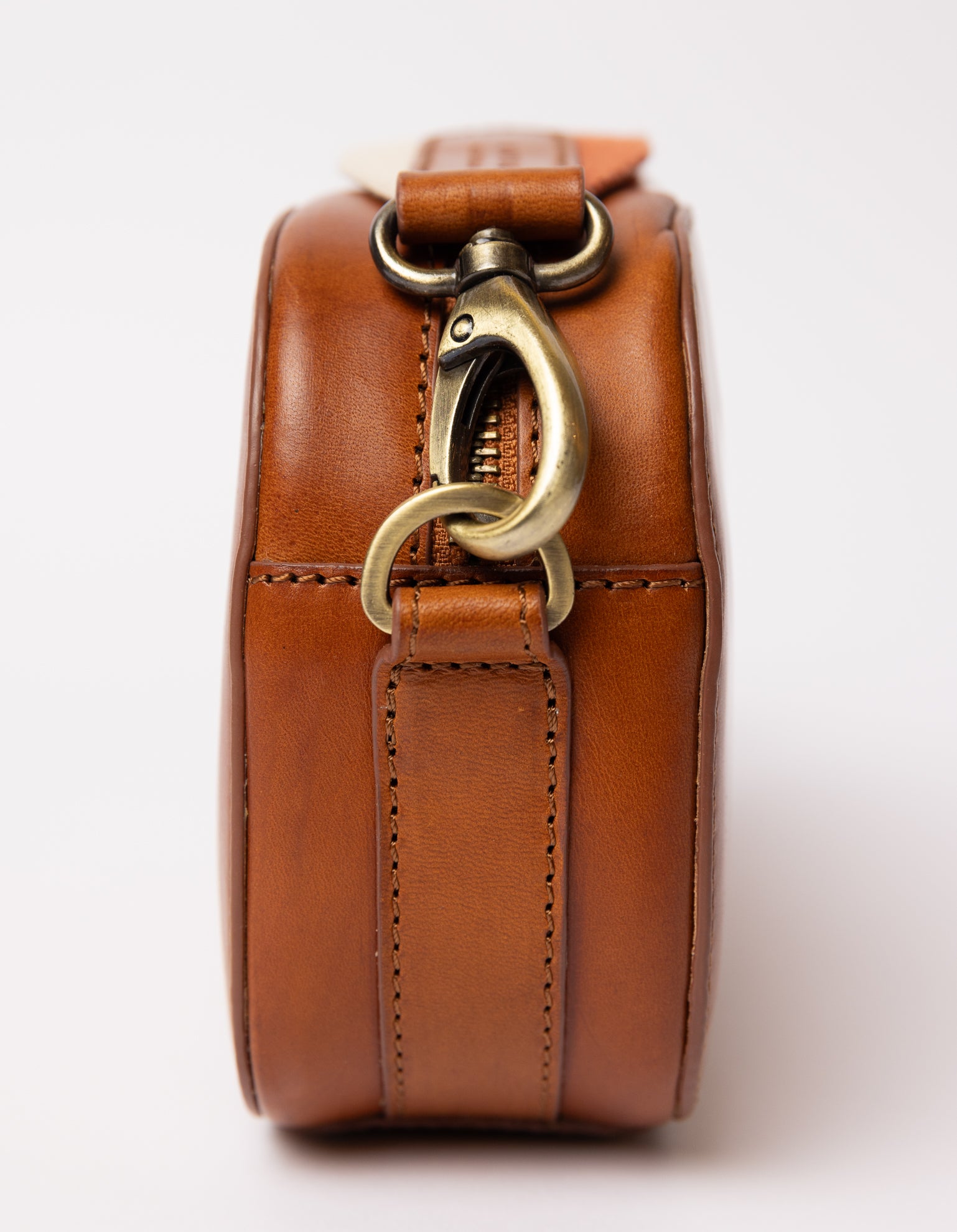 side of cognac bag on white background -close up of strap carabiner hooked on the bag from the side