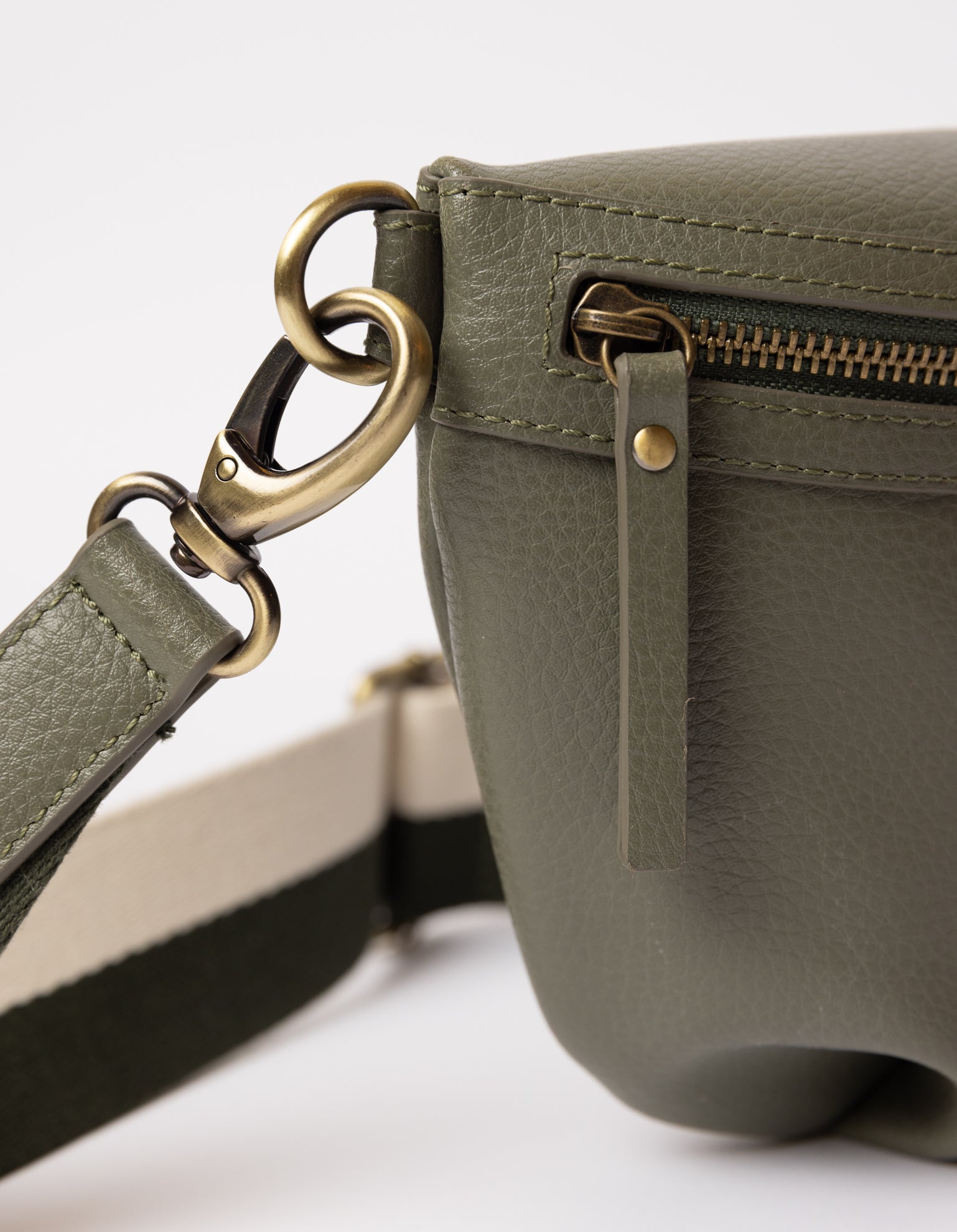 vegan green bag on white background - close up of strap carabiner hooked on bag and zipper handle