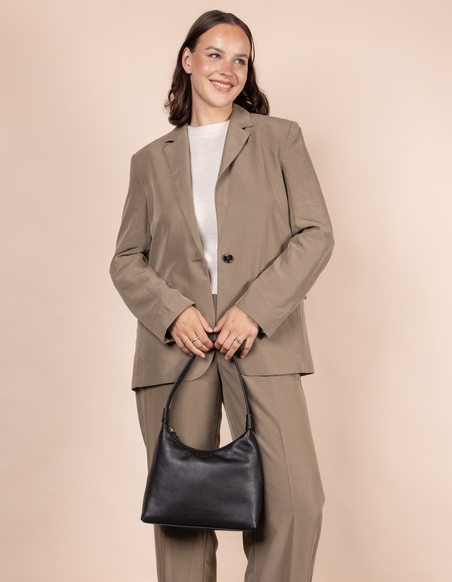 Female model holding Nora bag in black soft grain leather