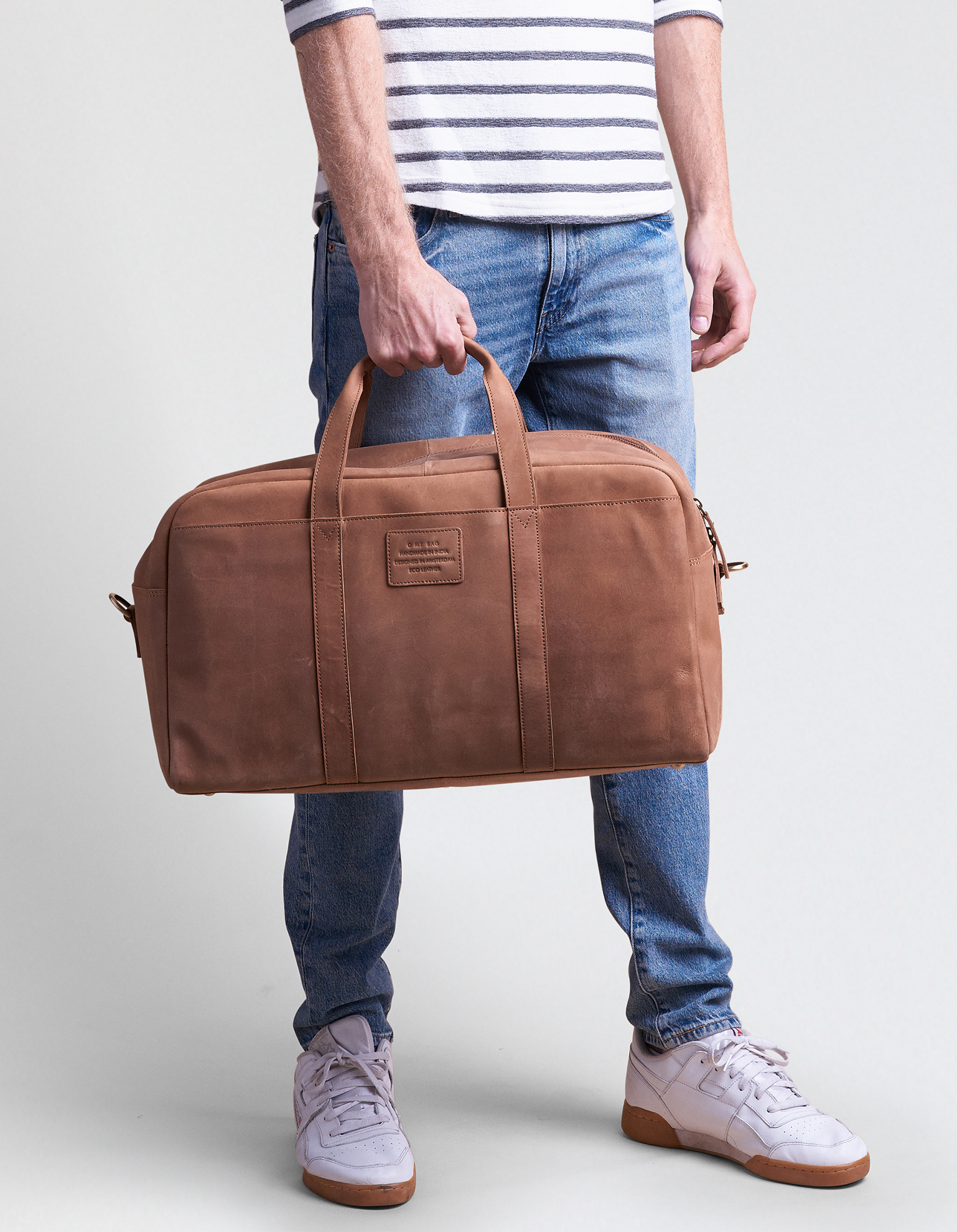 Male model holding brown leather weekender bag