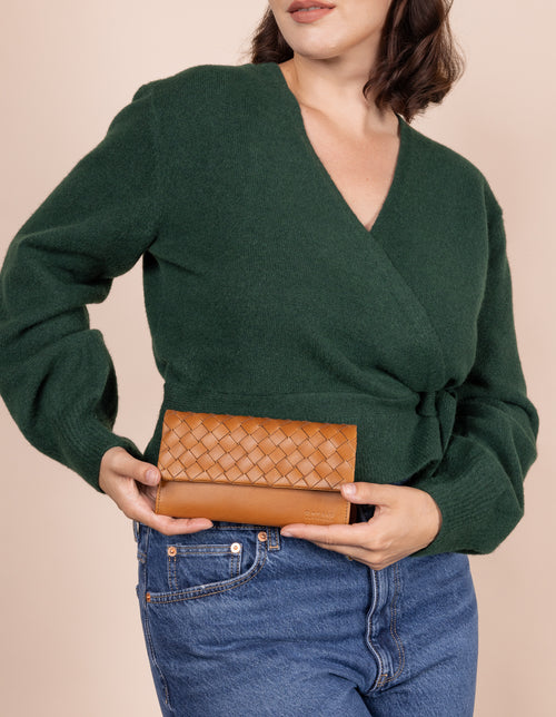 Model holding Pau's Pouch in woven cognac leather