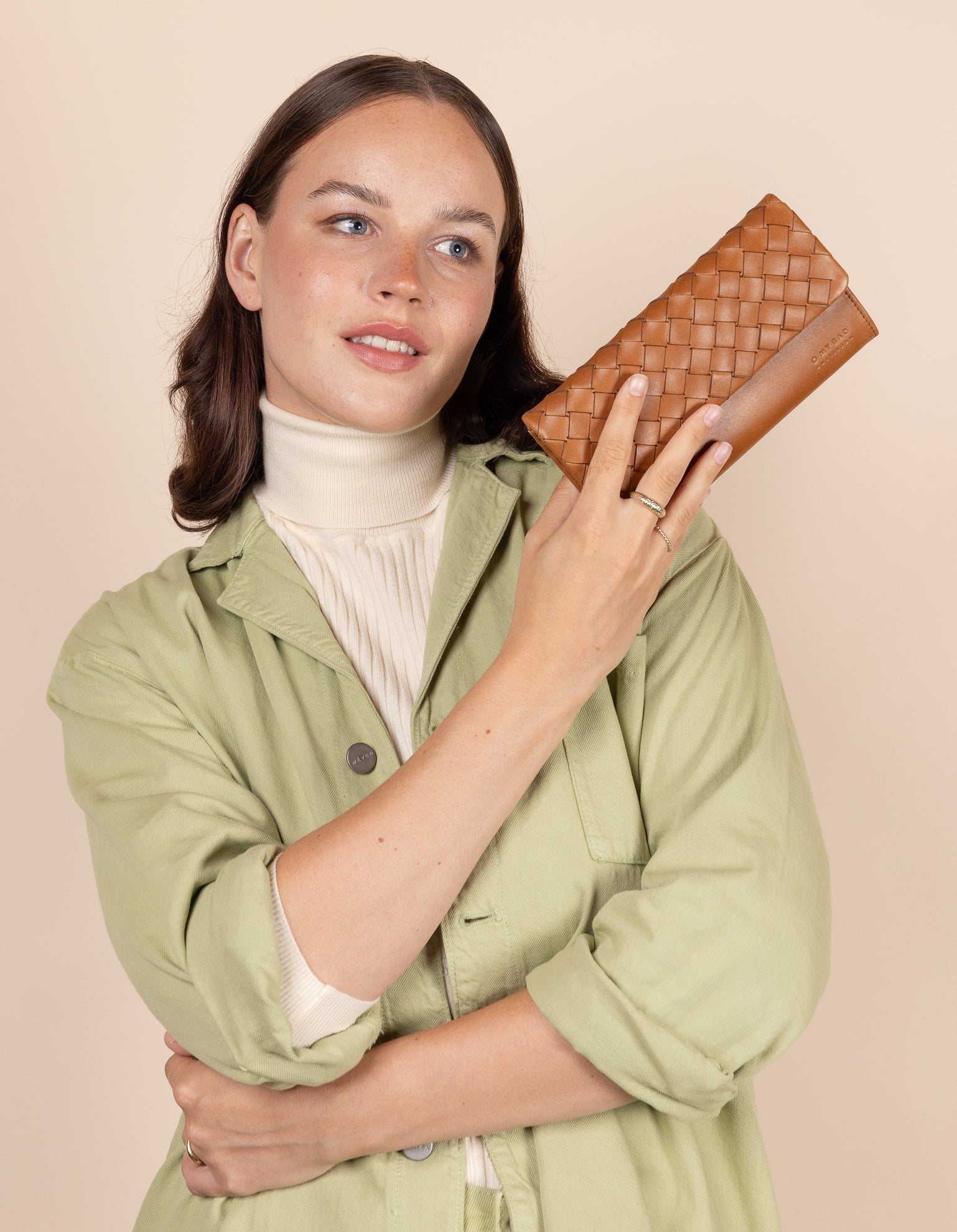 Model holding Pau's Pouch in woven cognac leather