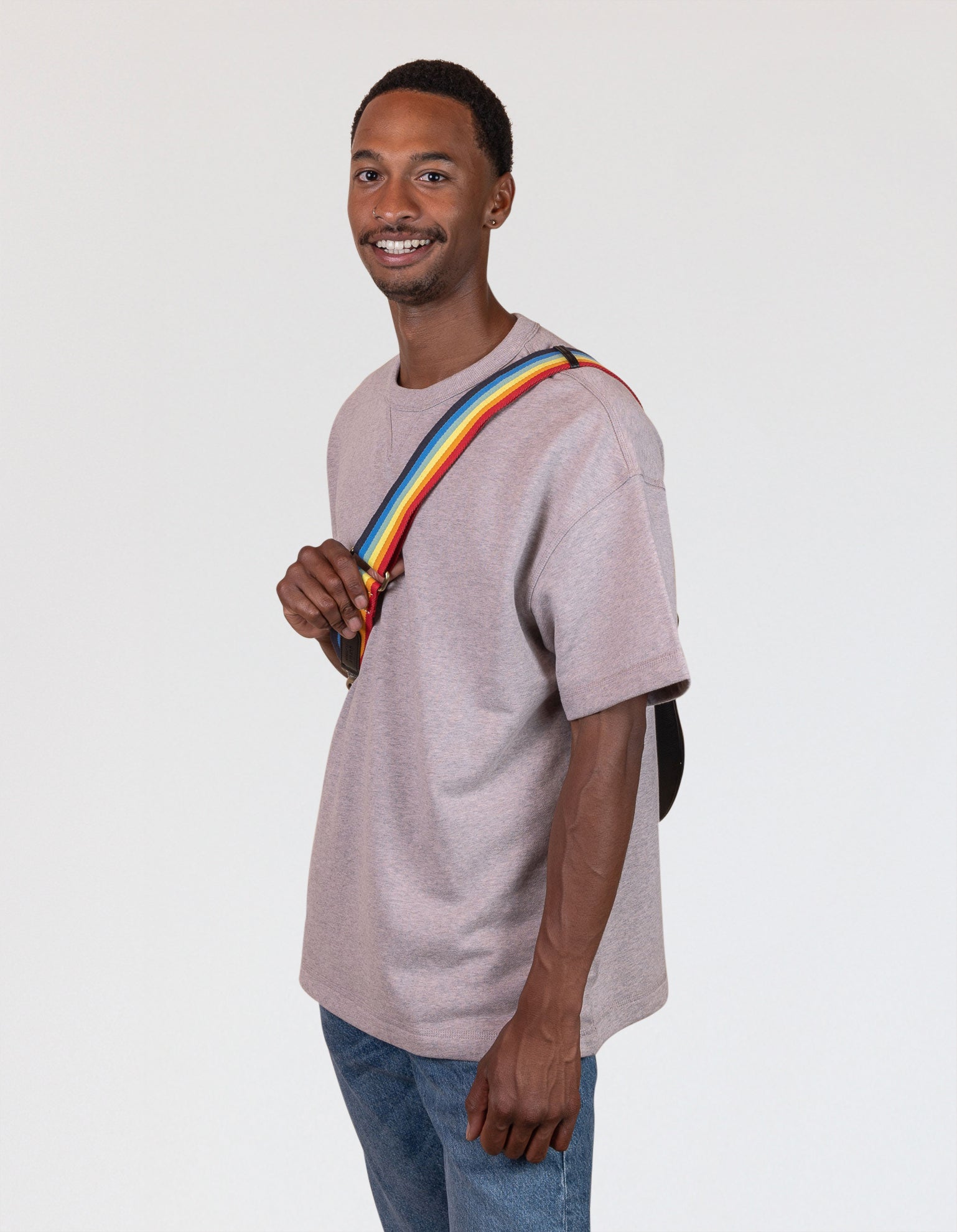 Rainbow webbing strap with black classic leather details. Male model image.