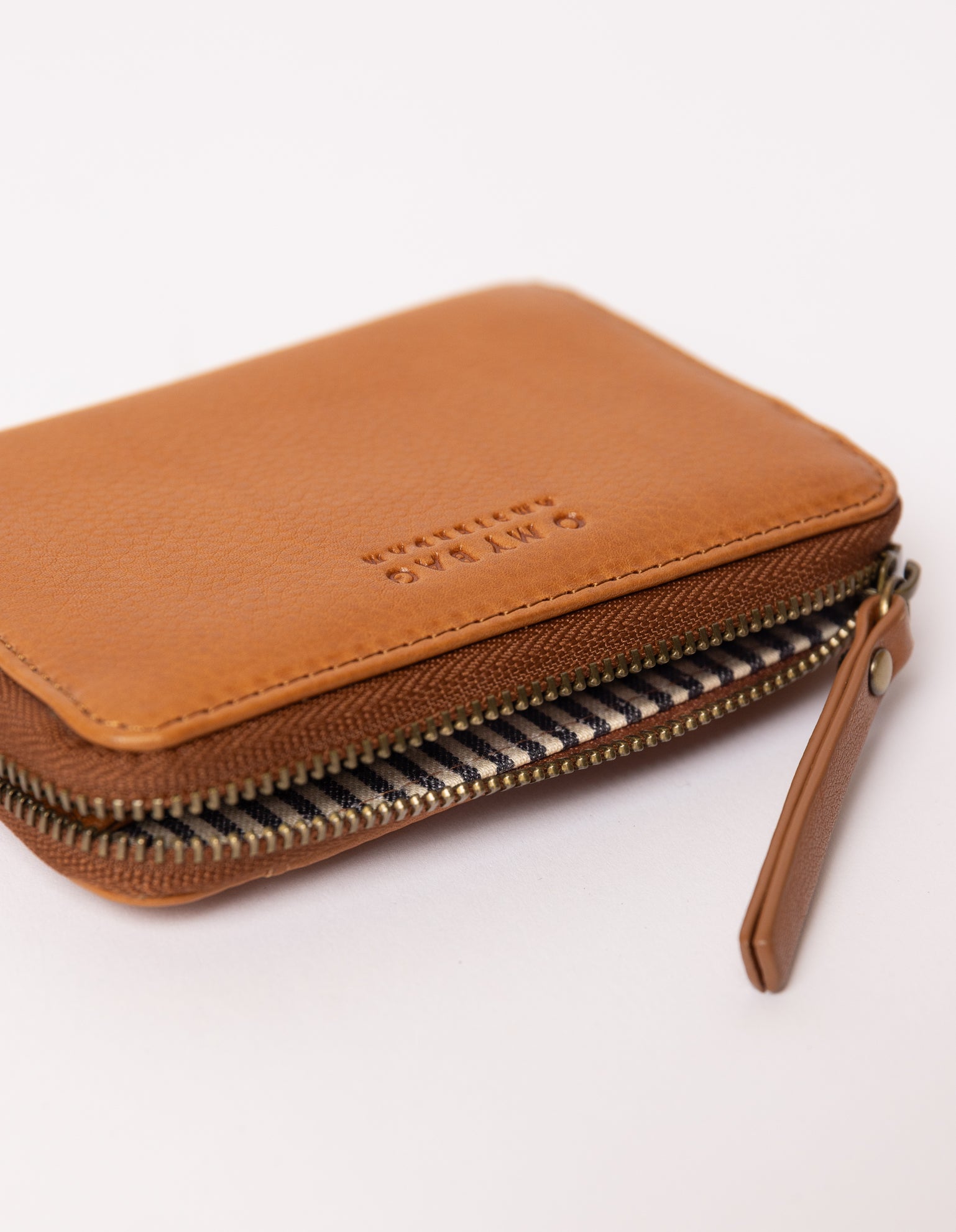 cognac wallet laid down on white background - close up of open zipper and zipper handle