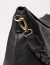 black bag on white background - close up of braided strap hooked on the bag from the side