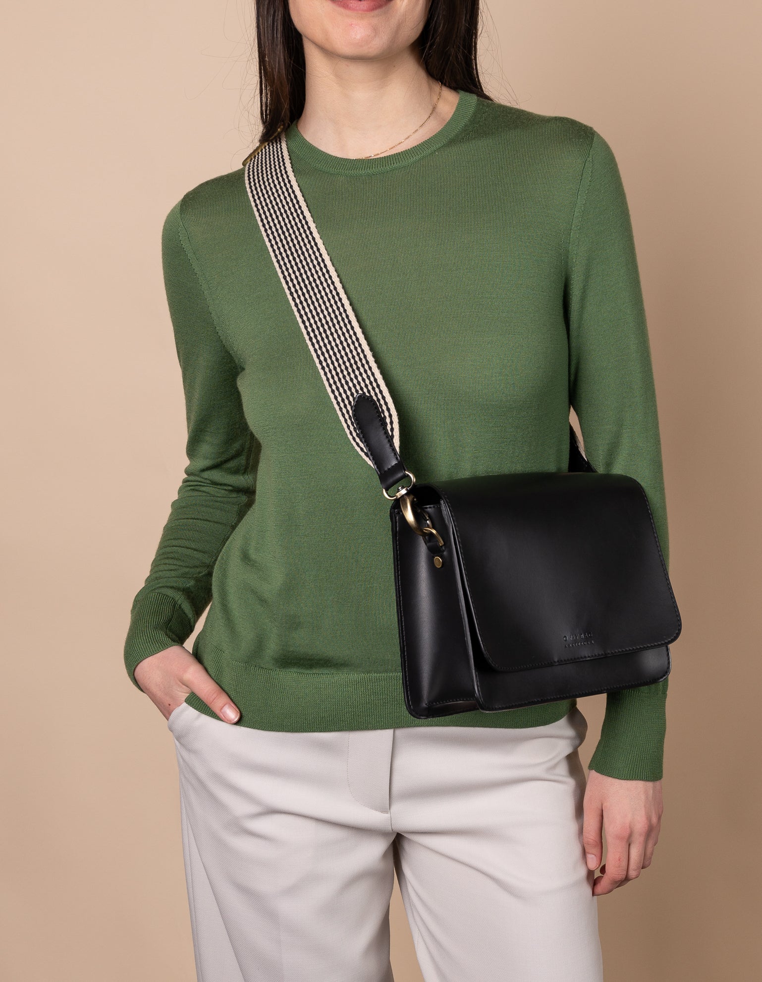 Model wearing brown crossbody bag with black and white strap
