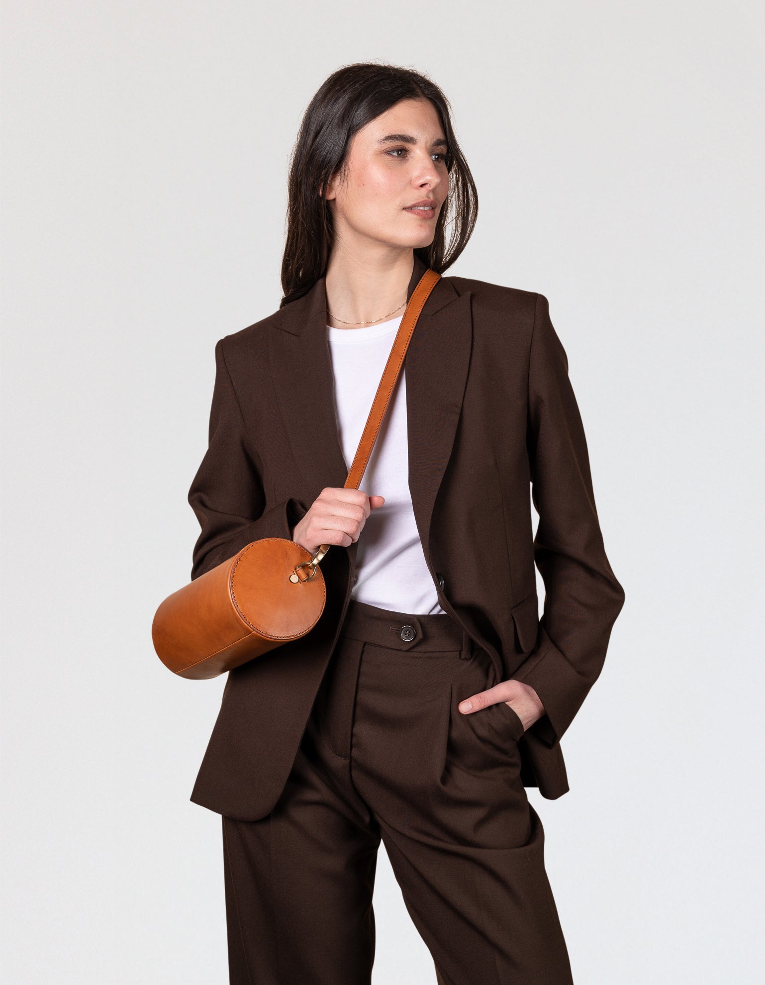 Model wearing brown suit and brown cylinder bag crossbody