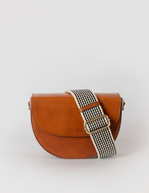 Ava saddle bag with checkered webbing strap. Front product image - cognac classic leather.