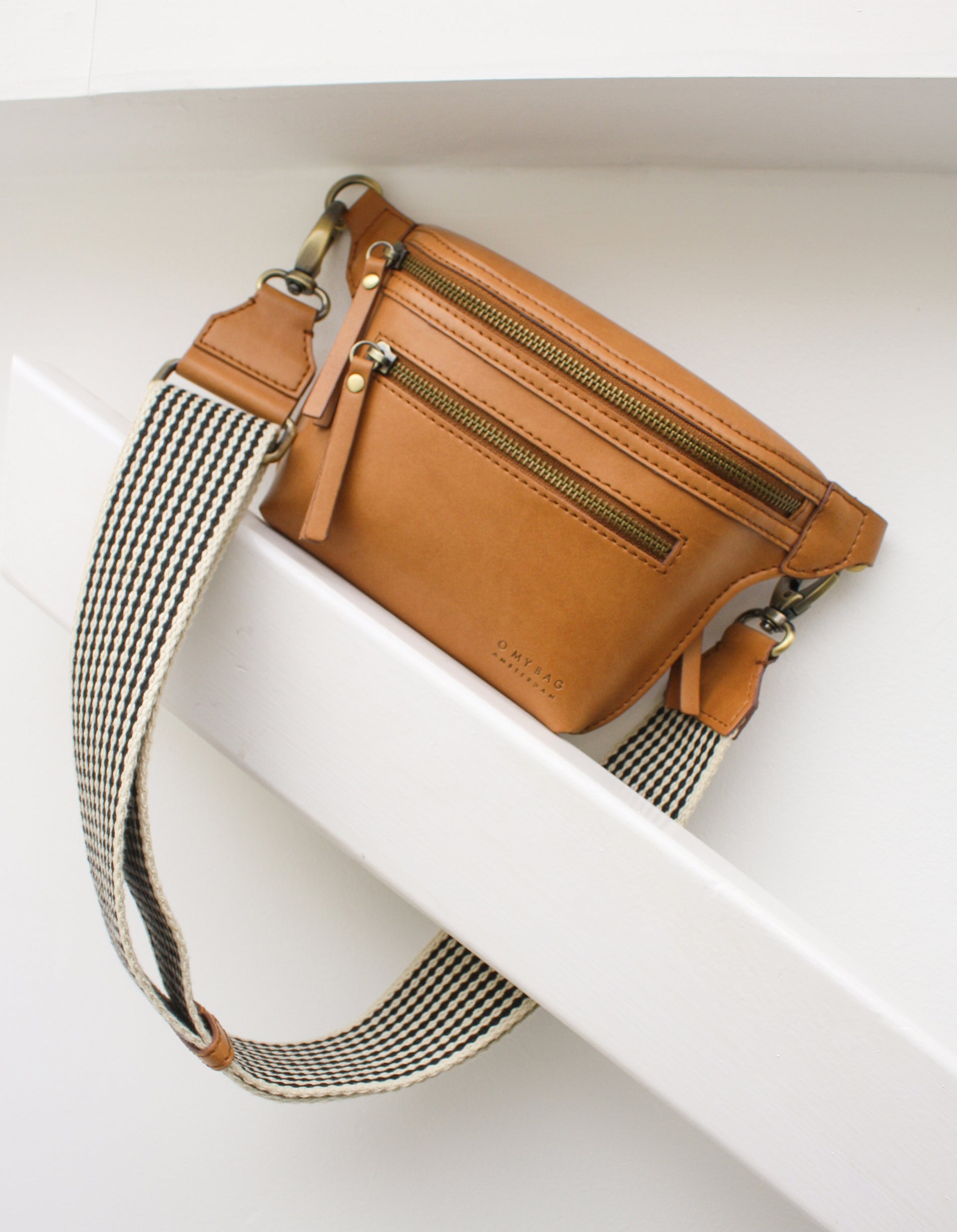 Becks Bum Bag in cognac apple leather - back product shot with checkered webbing strap lifestyle image