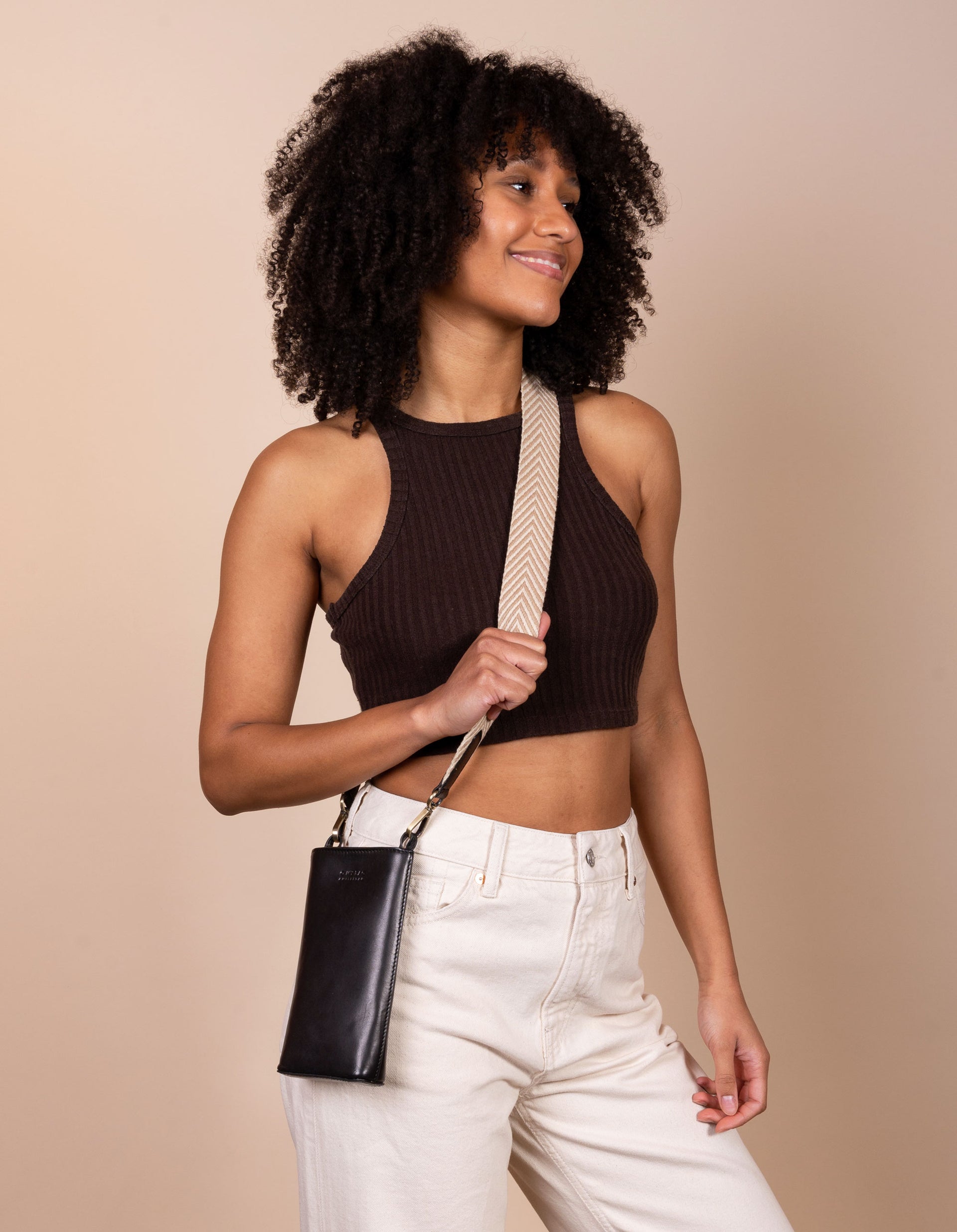 Charlie phone bag - black classic leather - female model product image with the webbing strap