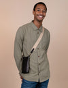 Charlie phone bag - black classic leather - male model product image with the webbing strap
