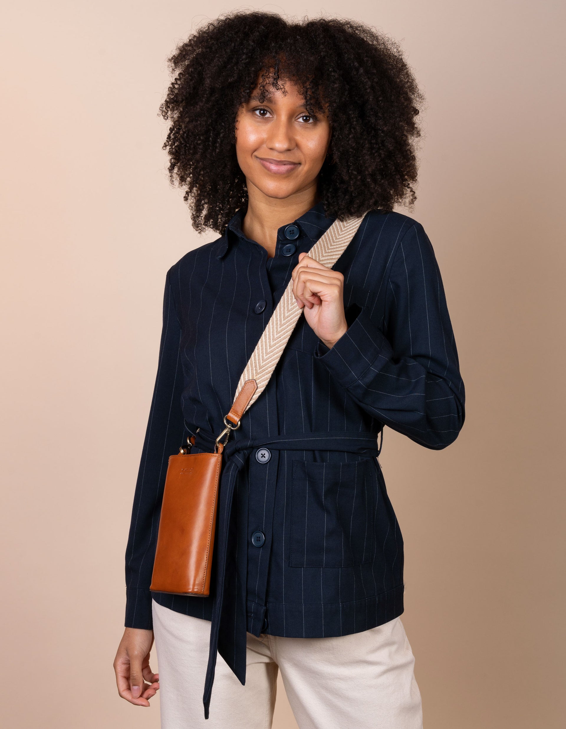 Charlie phone bag - cognac classic leather - female model product image with organic cotton webbing strap