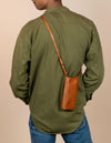 Charlie phone bag - cognac classic leather - male model product image with adjustable leather strap