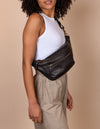 Drew Bum Bag in black soft grain leather - female model product image with leather strap