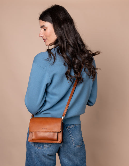 Harper Mini cognac Leather crossbody handbag. Model product image