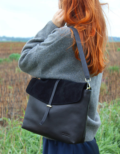 Black Soft Grain & Suede leather womens handbag. Square shape with an adjustable strap. Lifestyle image.