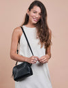 Black Leather womens handbag. Square shape with an adjustable strap. Model image.